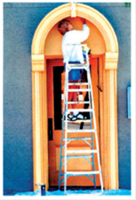 A man uses a ladder to paint the porch roof.