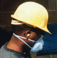 Construction worker wearing a hard hat and a dust mask.